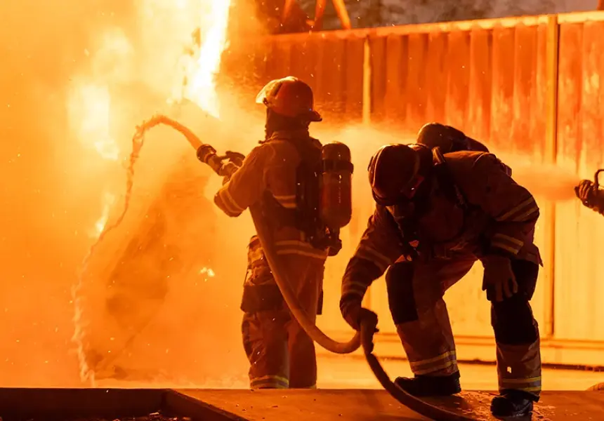 Two fire-fighters combating a blaze