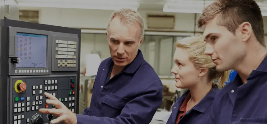 Two men and a woman in front of a mechanical panel with buttons and dials